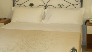 A bed with white linens and a floral-patterned duvet cover. - Hotel Athena (Spoleto)