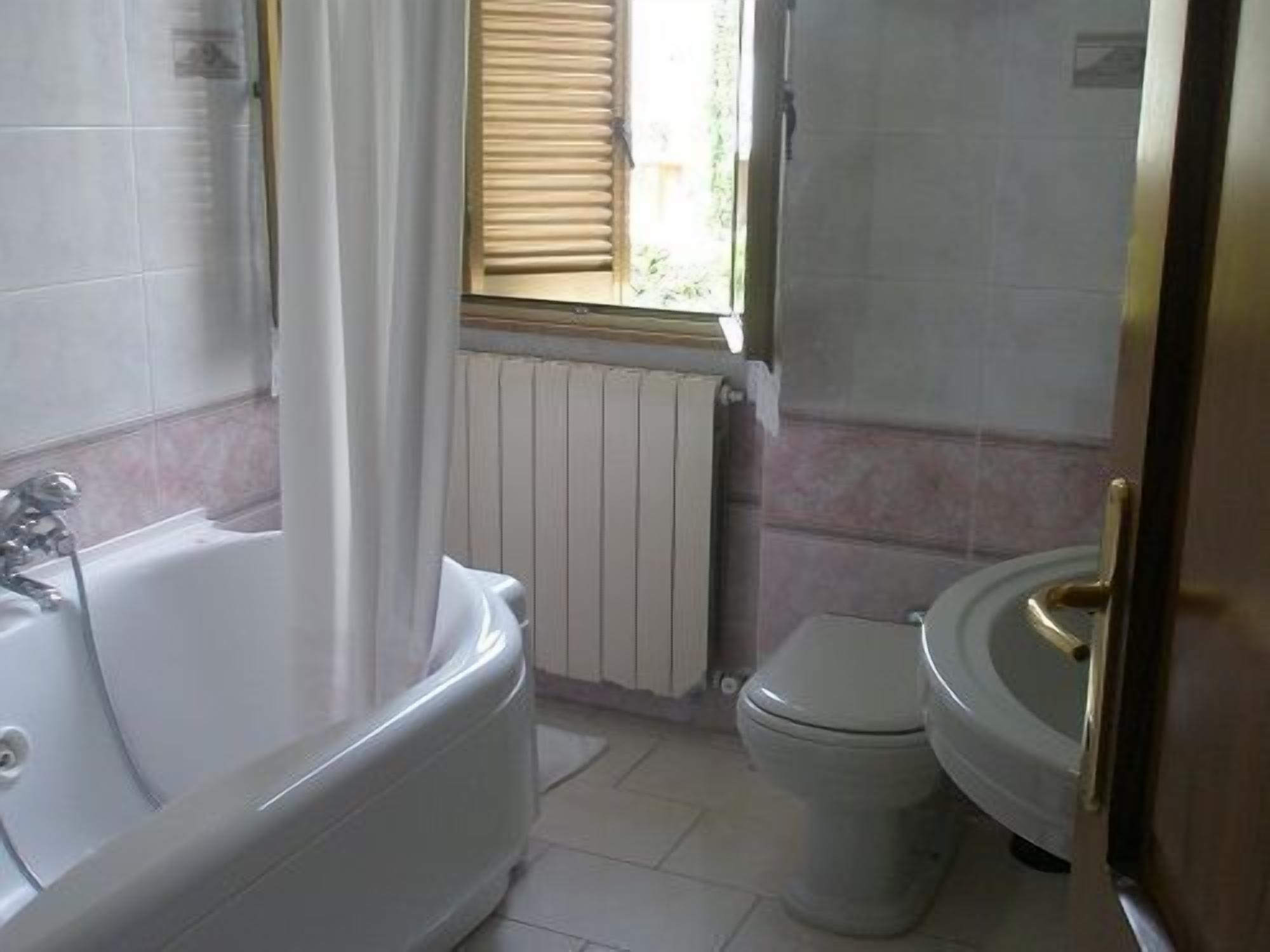 Un bagno con vasca, servizi igienici e una finestra con persiane.