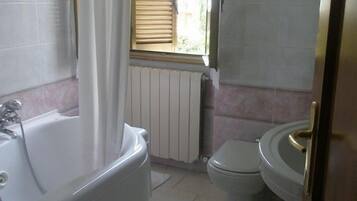 Un bagno con vasca, servizi igienici e una finestra con persiane.