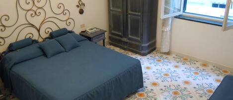 A bedroom with a bed, a wardrobe, a bedside table, and a window.