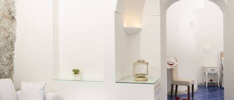 Um banheiro moderno e minimalista com paredes brancas, prateleira de vidro e chão com azulejos azuis.