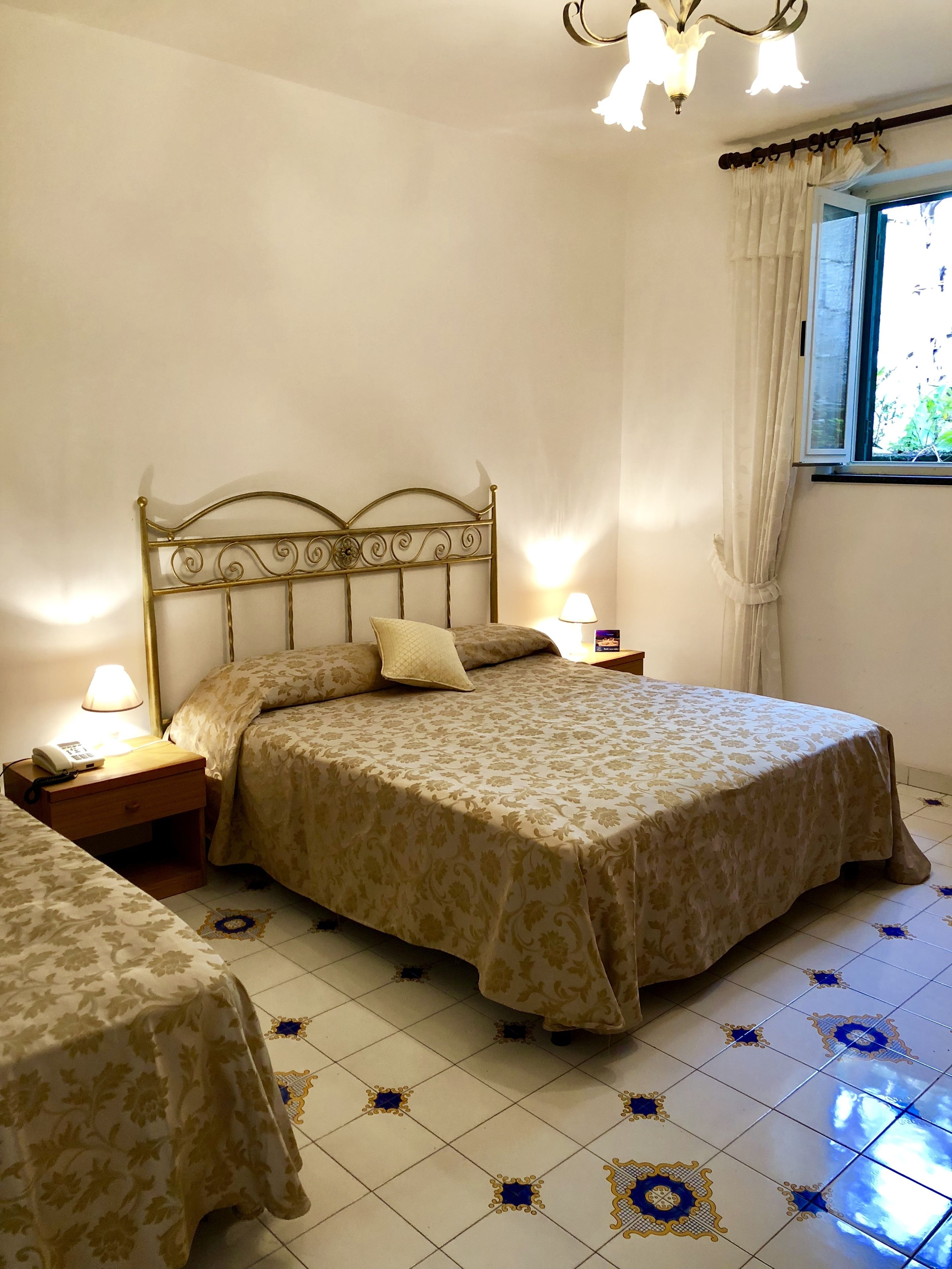 A bedroom with a bed, bedside tables, a lamp, and a window with curtains.