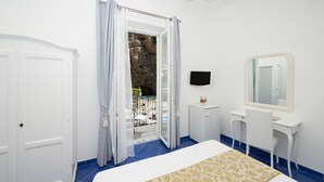 A bedroom with a bed, a desk, a mirror, and a door leading to a balcony. - Alfonso a Mare (Furore)