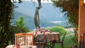 An outdoor dining area with a table set for four, surrounded by greenery and a mountain view. - Hotel Tenuta di Canonica (Todi)