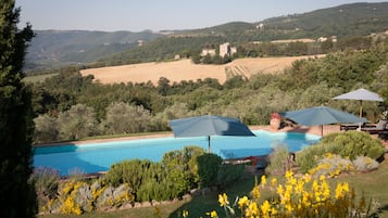 Una piscina rodeada de exuberante vegetación y colinas al fondo.