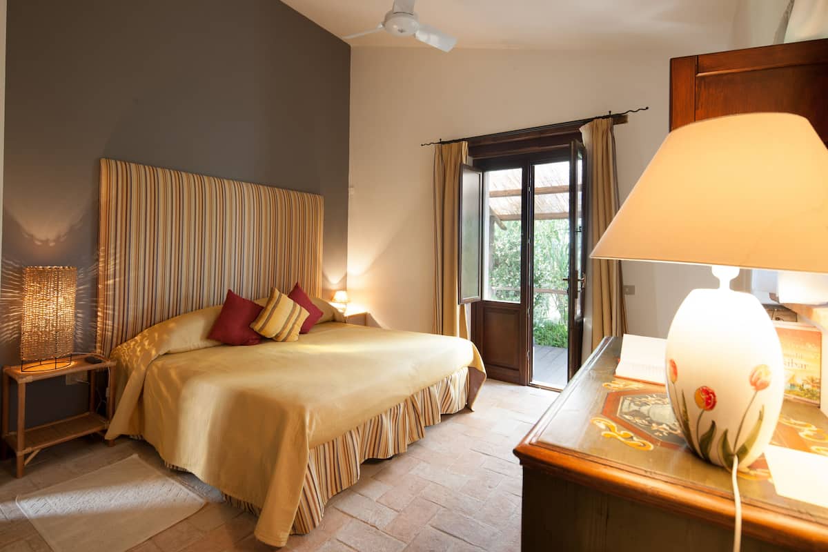 A hotel room with a bed, a desk, a lamp, a window, and curtains.