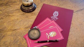 A hotel room with a wooden table, a bell, a pen, and a keychain with the hotel's name.