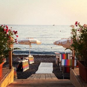 A wooden deck leading to a beach with white umbrellas and colorful chairs. - Tirreno (Sapri)