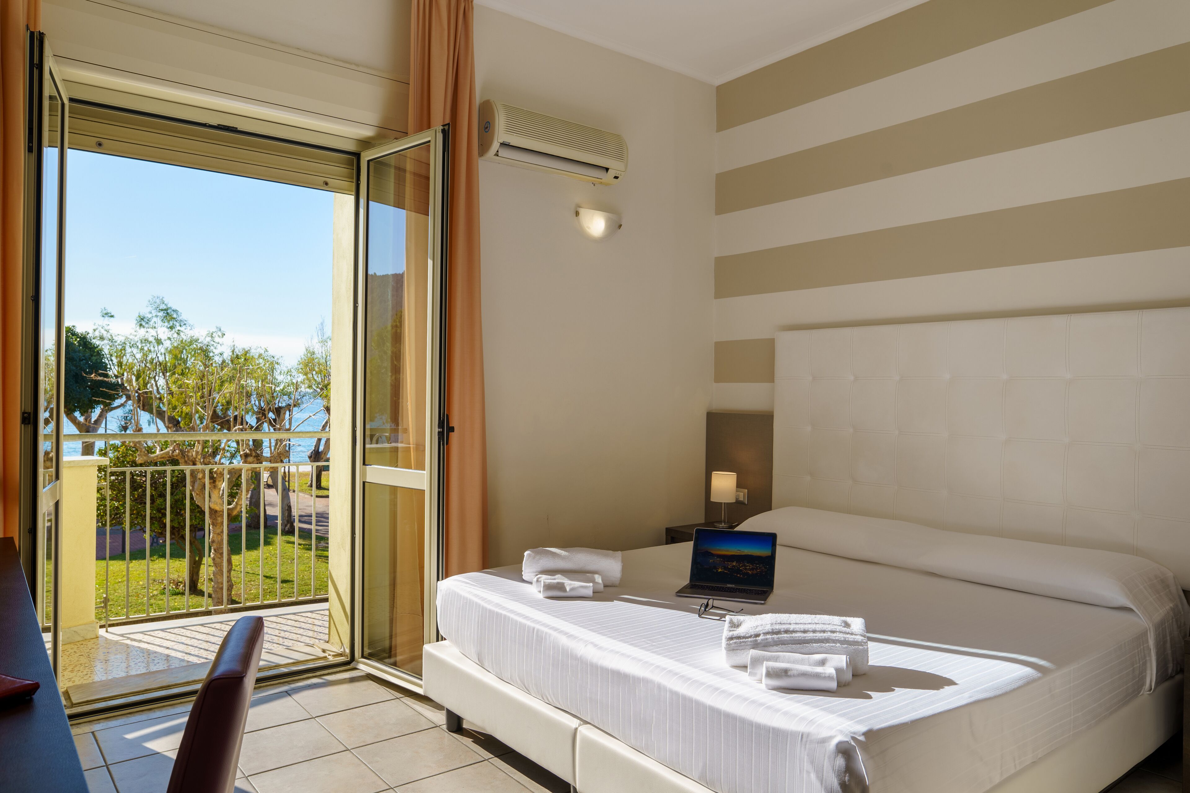 Une chambre d’hôtel avec un lit, un ordinateur portable et une vue sur l’extérieur.