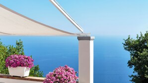 A balcony with a view of the sea, a white column, and two potted plants with pink flowers. - Albergo Diffuso Bacco Furore (Furore)