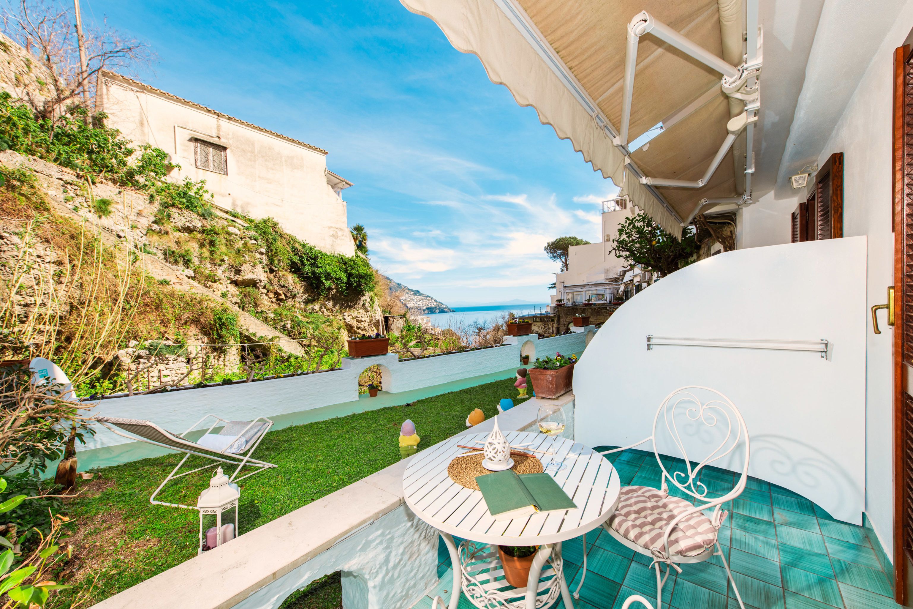 A patio area with a table and chairs, a small pool, and a view of the sea.