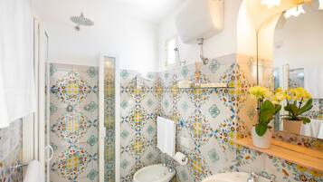 Ein Badezimmer mit Dusche, Bidet, Waschbecken und einem Spiegel mit Blumenmuster-Fliesen.