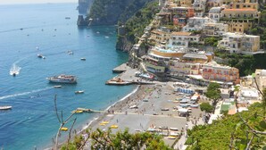 A coastal town with colorful buildings, a beach, and boats on the water. - Casa Guadagno (Positano)