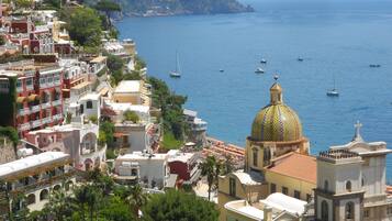 A coastal town with a prominent golden-domed building, terraced houses, and a clear view of the sea with boats.