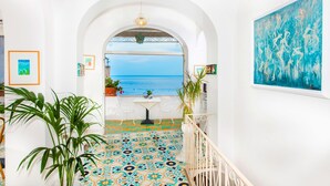 A hallway with a view of the sea, a tiled floor, and a painting on the wall. - Casa Guadagno (Positano)