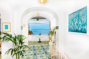 Un pasillo con vista al mar, suelo de baldosas y un cuadro en la pared.