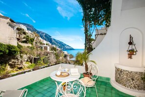 A terrace with a table, chairs, and a potted plant. - Casa Guadagno (Positano)