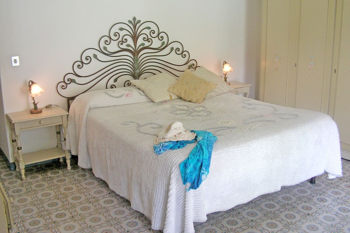 Um quarto com uma cama, duas mesas de cabeceira, um criado-mudo e um guarda-roupa.