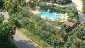 Une grande maison avec une piscine, entourée de verdure.