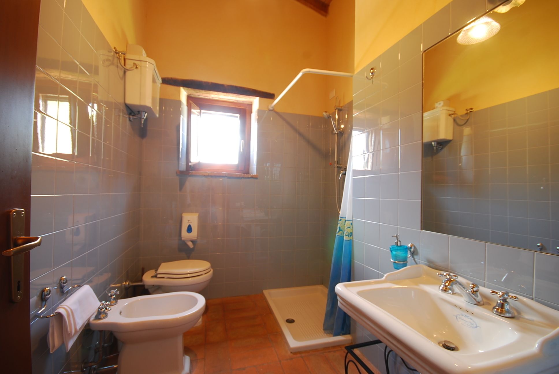 A bathroom with a toilet, bidet, shower, and sink.
