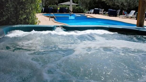 Un bain à remous avec vue sur une piscine et des chaises longues.