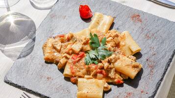 A plate of pasta with a tomato-based sauce, garnished with parsley, on a slate serving board.