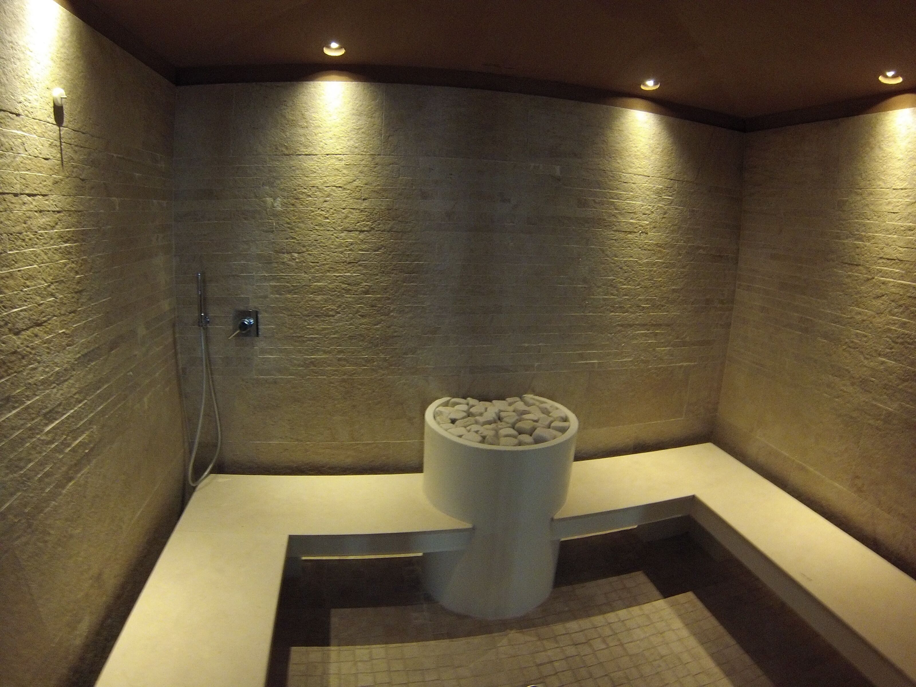 Un baño moderno con pared de piedra, bañera integrada y lavabo de piedra.