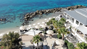 Un resort frente a la playa con asientos al aire libre, sombrillas y vistas al océano.