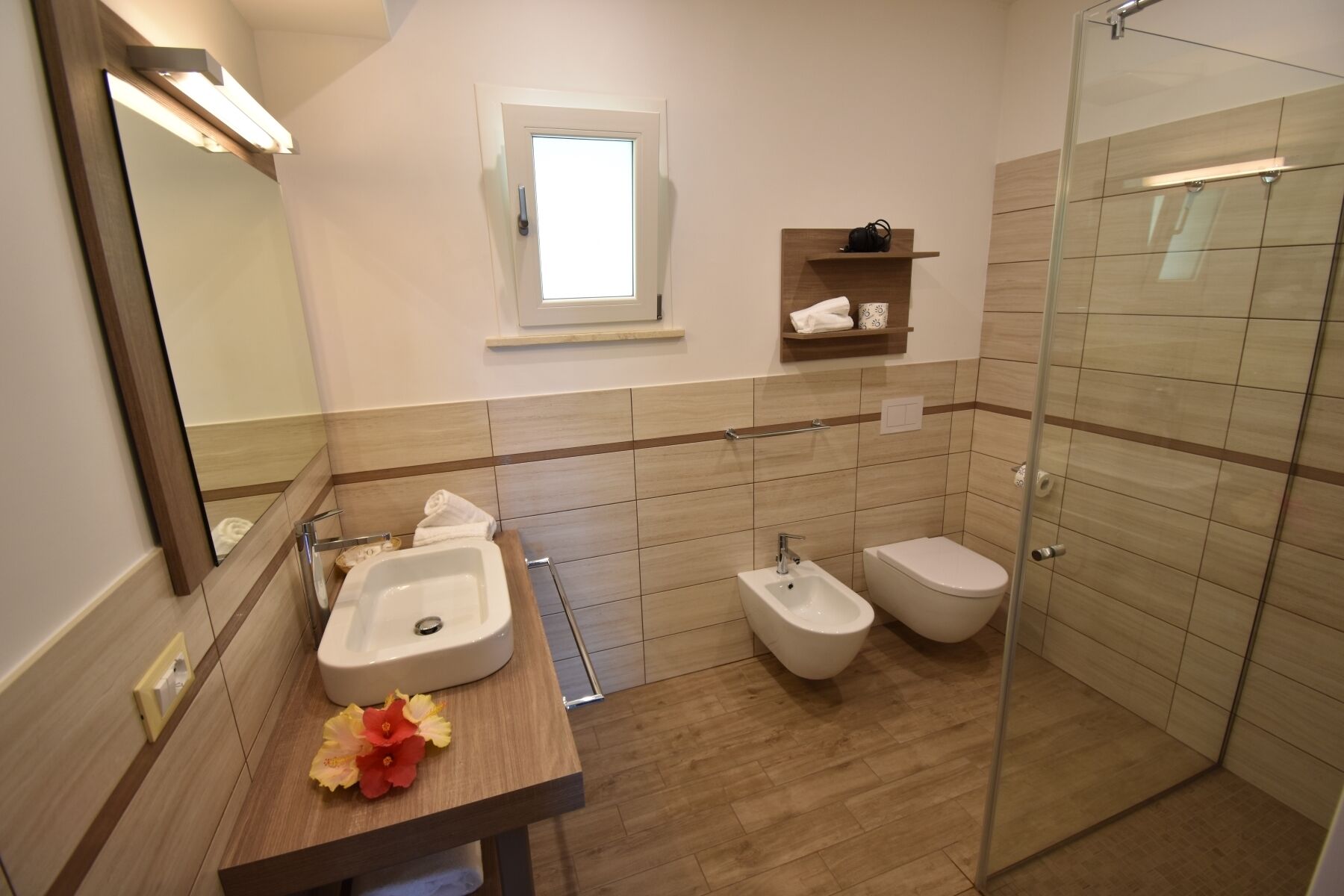 A modern bathroom with a sink, bidet, and glass-enclosed shower.