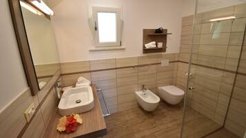 Un baño moderno con lavabo, bidé y ducha con mampara de vidrio.