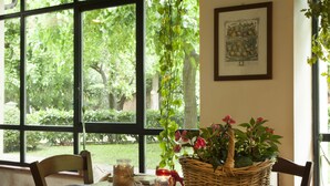 A room with a large window, a wicker basket with flowers, a candle, and a book on a table. - Il Granaio dei Casabella (Capaccio-Paestum)