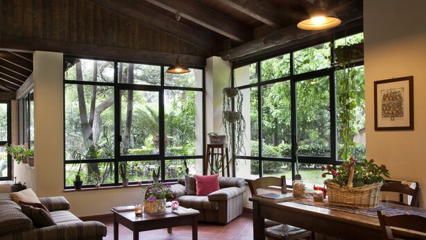 A spacious living area with large windows, a sofa, a dining table, and a hanging plant. - Il Granaio dei Casabella (Capaccio-Paestum)