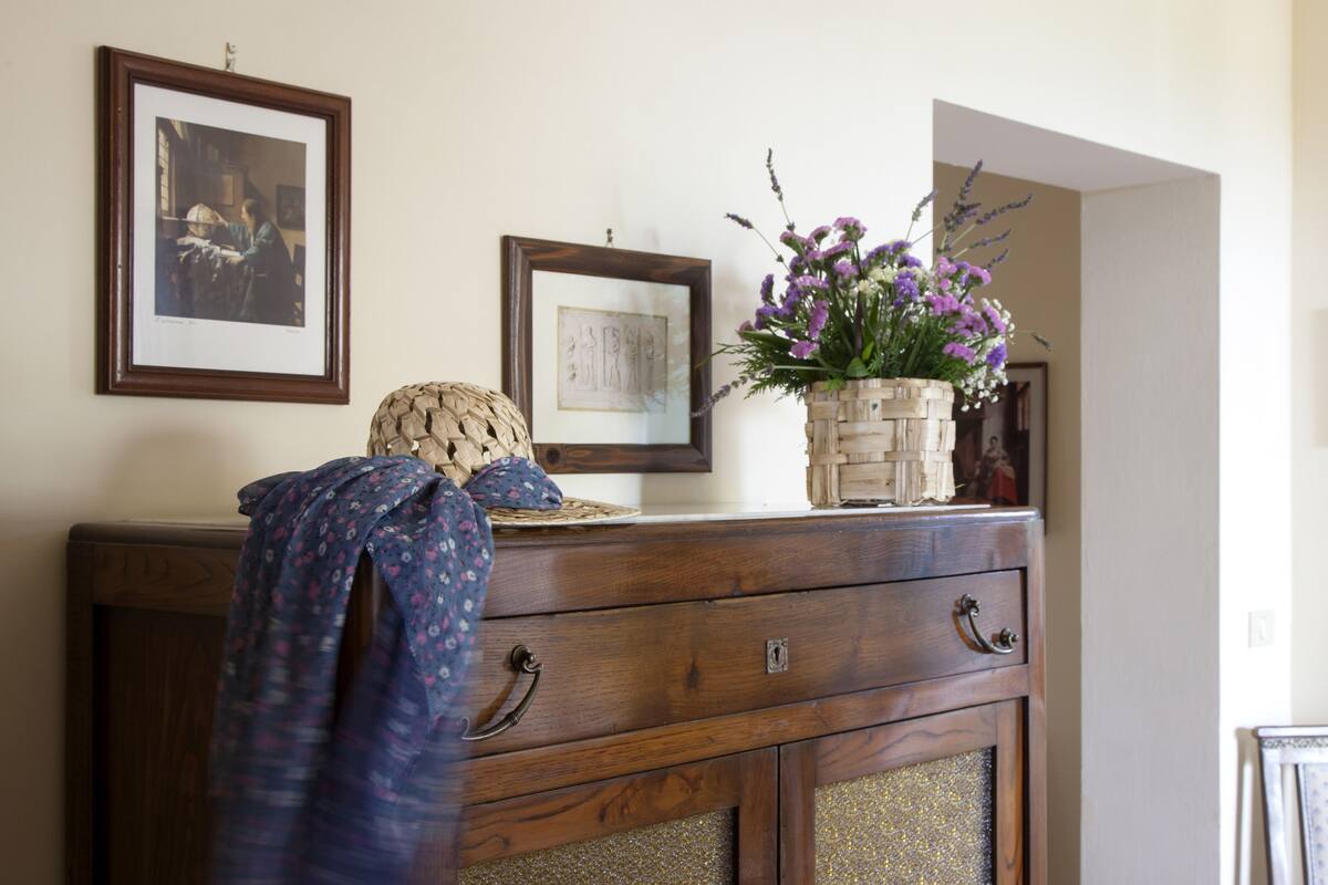 A wooden dresser with a woven basket and a vase of flowers on top.