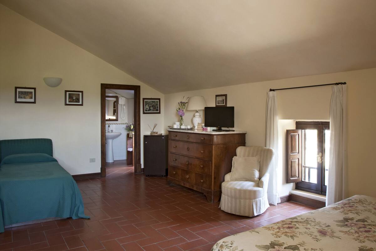 A bedroom with a bed, a dresser, a chair, and a television.
