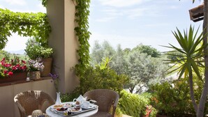 A patio with wicker chairs, a table set with breakfast, and potted plants. - Il Granaio dei Casabella (Capaccio-Paestum)