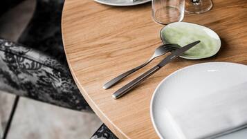 A neatly set dining table with a plate, fork, knife, and napkin, along with a glass of water and a menu.