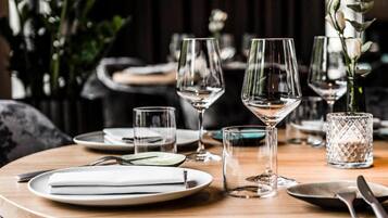 Un tavolo da pranzo apparecchiato con piatti, bicchieri e posate, illuminato da un moderno lampadario.