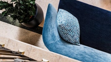 A modern chair with a blue cushion and a potted plant beside it.