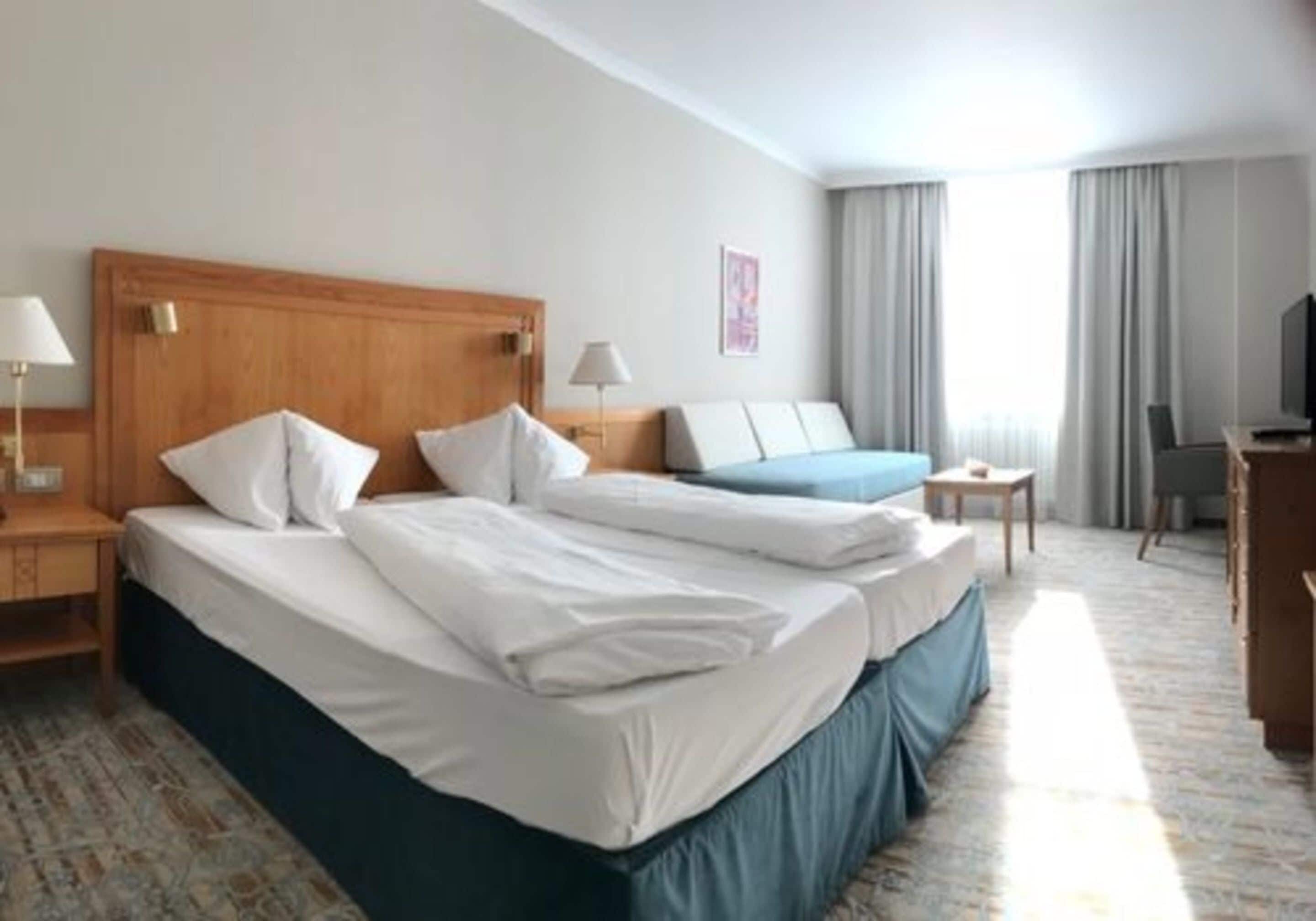 Une chambre d’hôtel avec deux lits, un bureau, une chaise et un téléviseur.