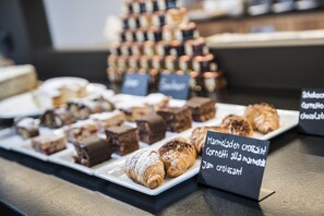A display of assorted pastries and desserts, including croissants and brownies, with a sign indicating a 'Marmladen croissant Cornetto alla Marmorata Jam croissant'.