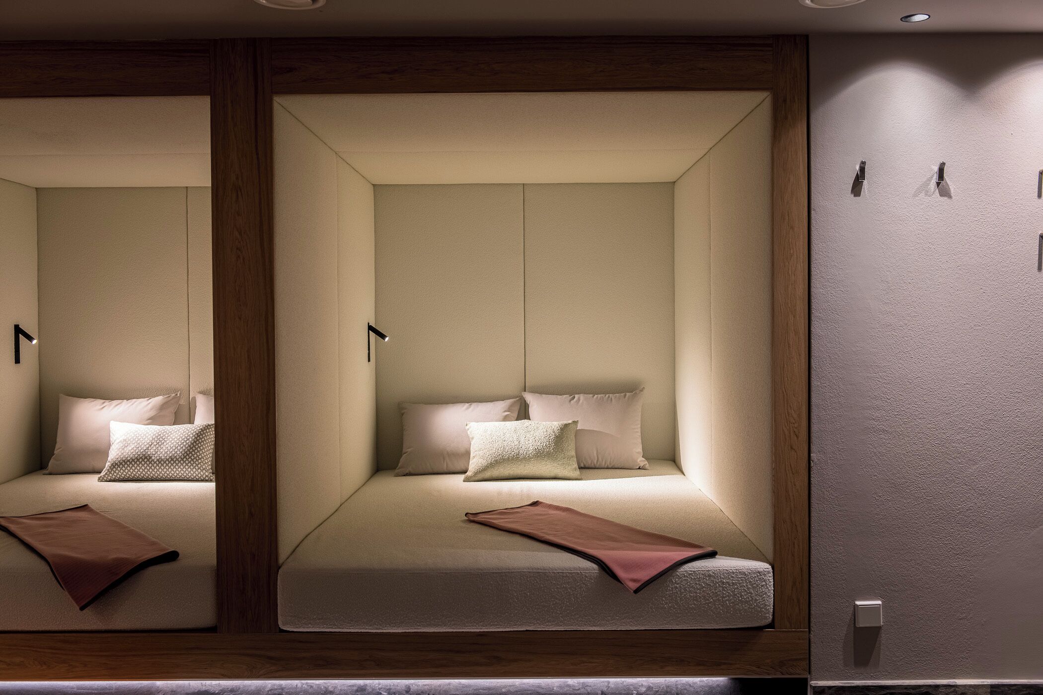 A room with two beds, each with pillows and a blanket, and a wooden panel on the wall.