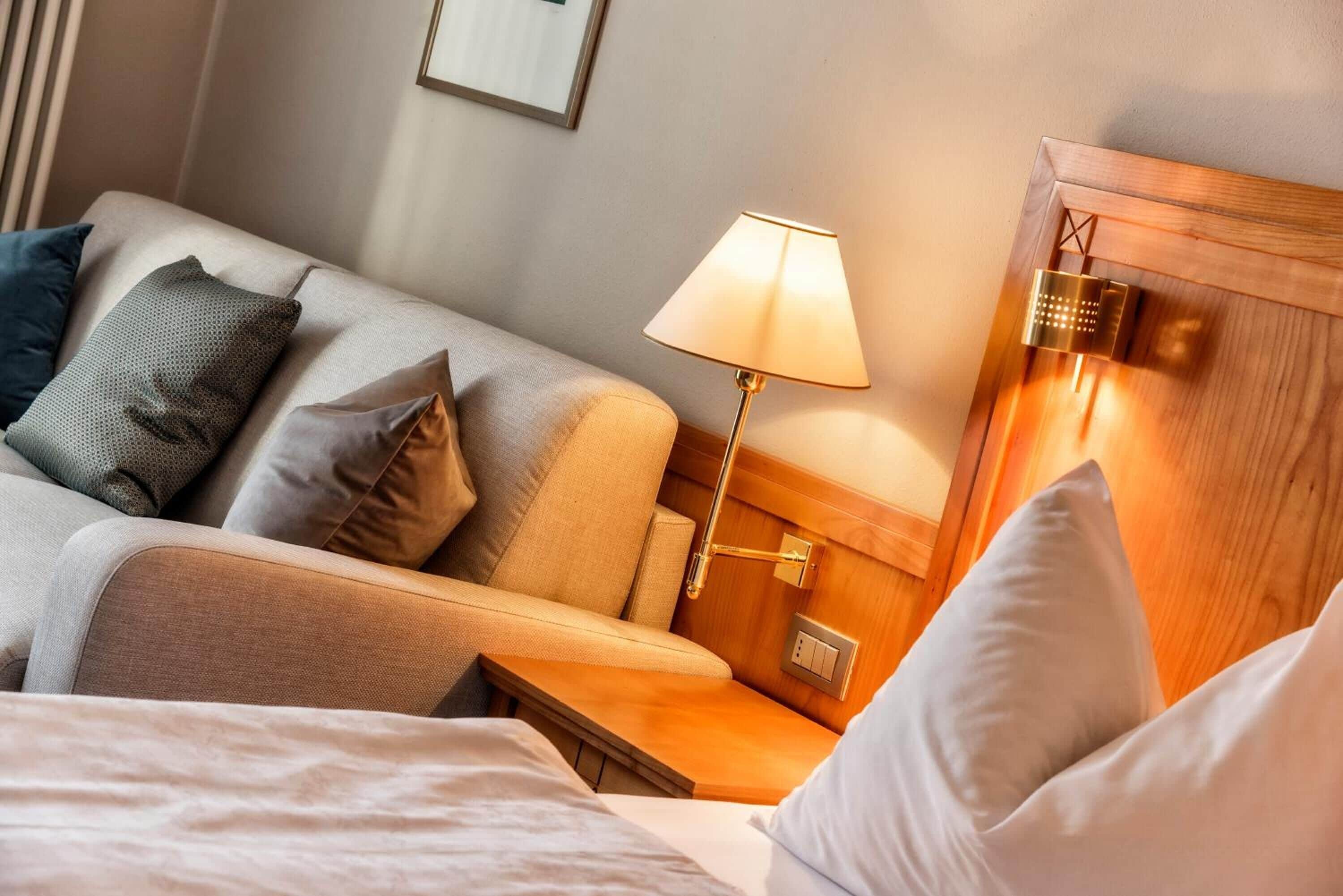 A hotel room with a bed, a nightstand, a lamp, and a wooden headboard.