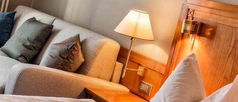 A hotel room with a bed, a nightstand, a lamp, and a wooden headboard.