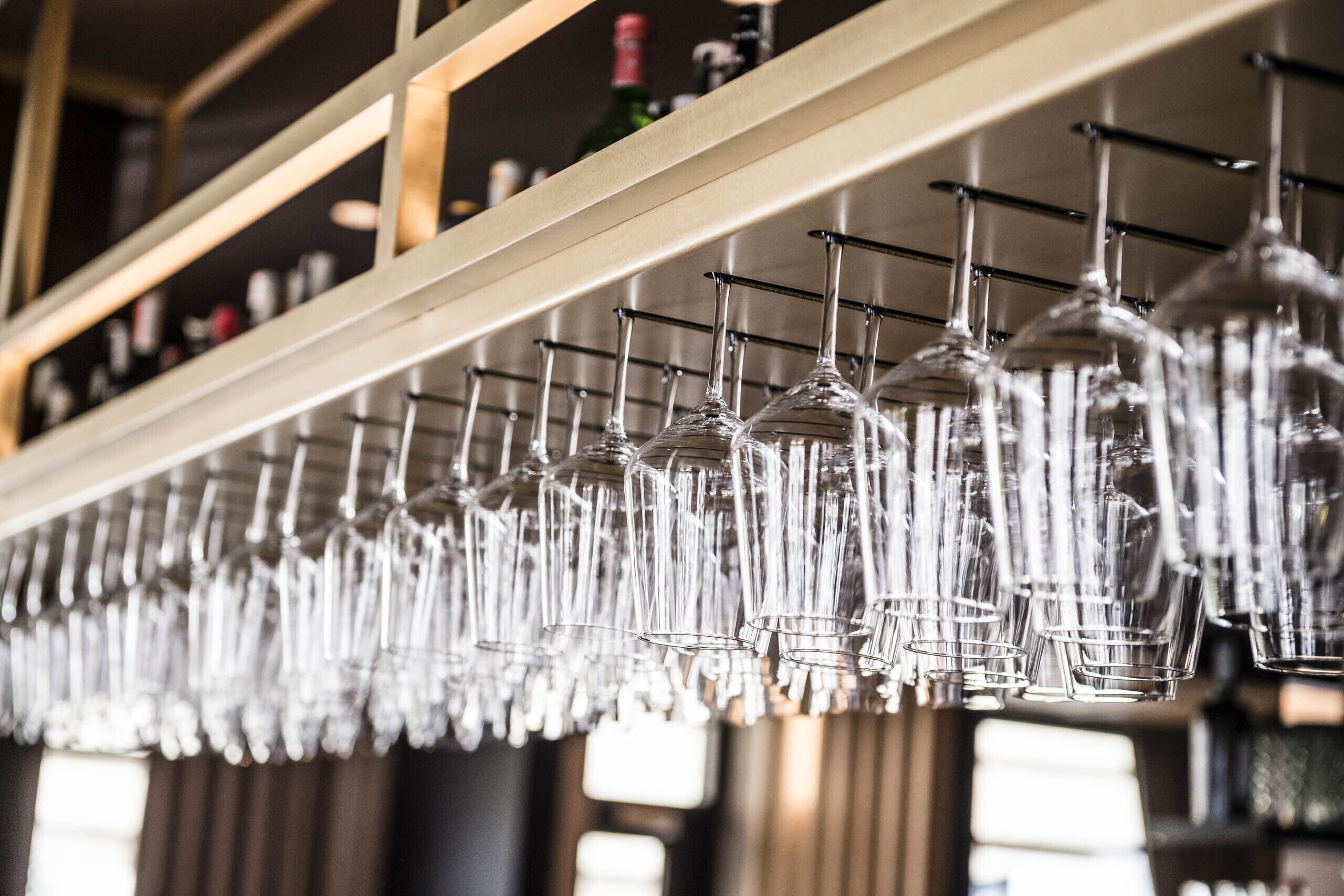 Una hilera de copas de vino colgando en un bar.