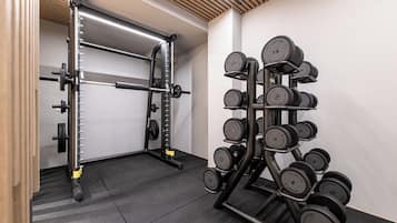 Ein Fitnessraum mit Hantelgestell, Langhantel und einer Reihe Kurzhanteln.