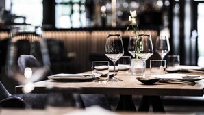 A dining table set with wine glasses, plates, and cutlery in a restaurant setting. - Hotel Post (Brunico)