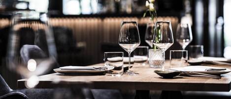 Una mesa de comedor dispuesta con copas de vino, platos y cubiertos en un restaurante.