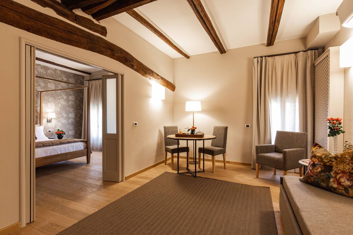 Une pièce bien éclairée, avec un lit, deux chaises, une table et un canapé.