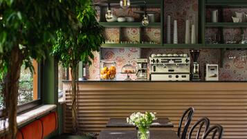 Un restaurante acogedor con una zona de asientos con bancos de madera, una mesa con un jarrón de flores y una cocina con electrodomésticos antiguos.
