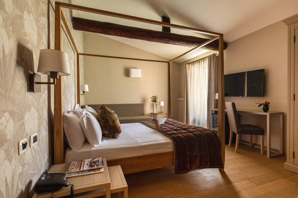 Une chambre d’hôtel comprenant un lit, une table de chevet, une lampe et un bureau avec une chaise.